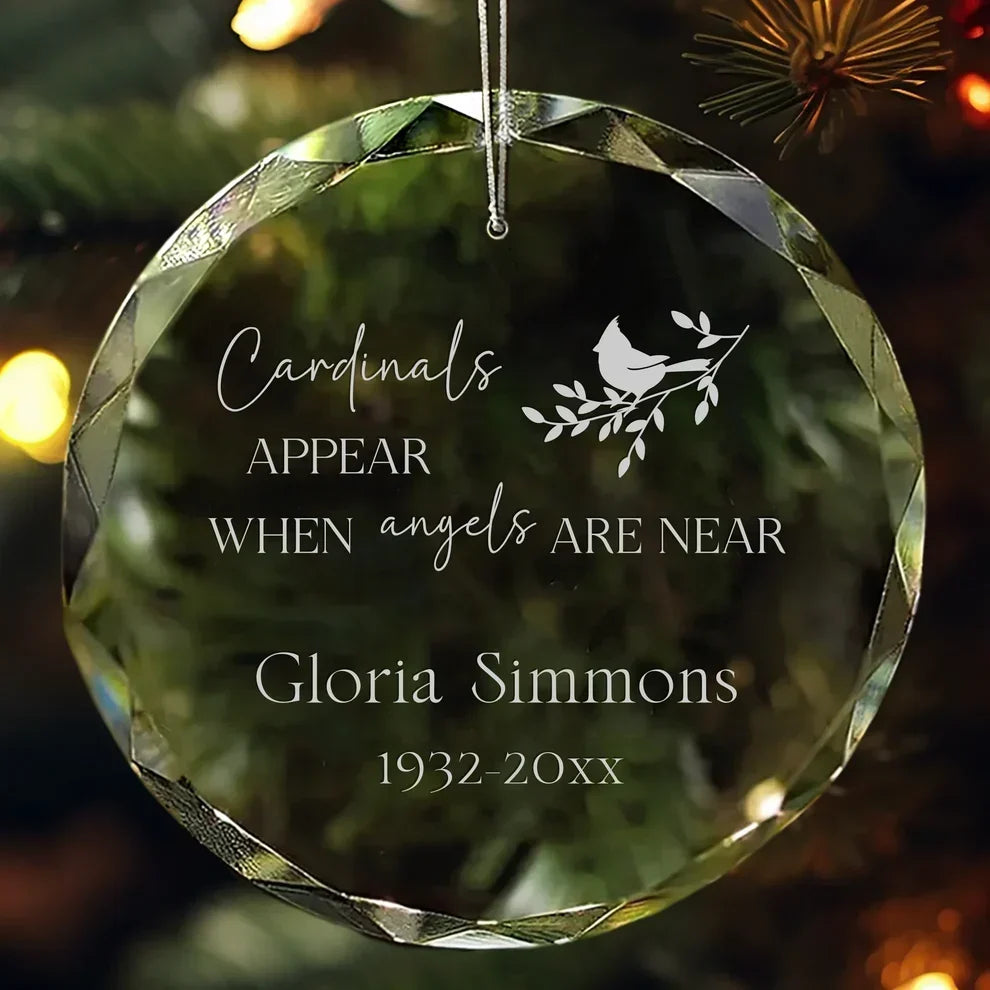 MyOrnament cardinal memorial ornament personalized with Gloria Simmons and dates, hanging against green branches.