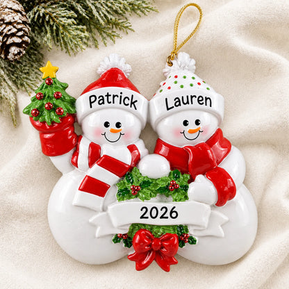 Personalized snowman couple christmas ornament laid on a soft white knit blanket