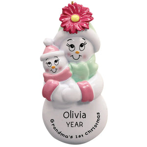 A personalized holiday ornament featuring a pink snowman with a flower, holding a smaller snowman, with the text 'Olivia Year' and the option to add names.