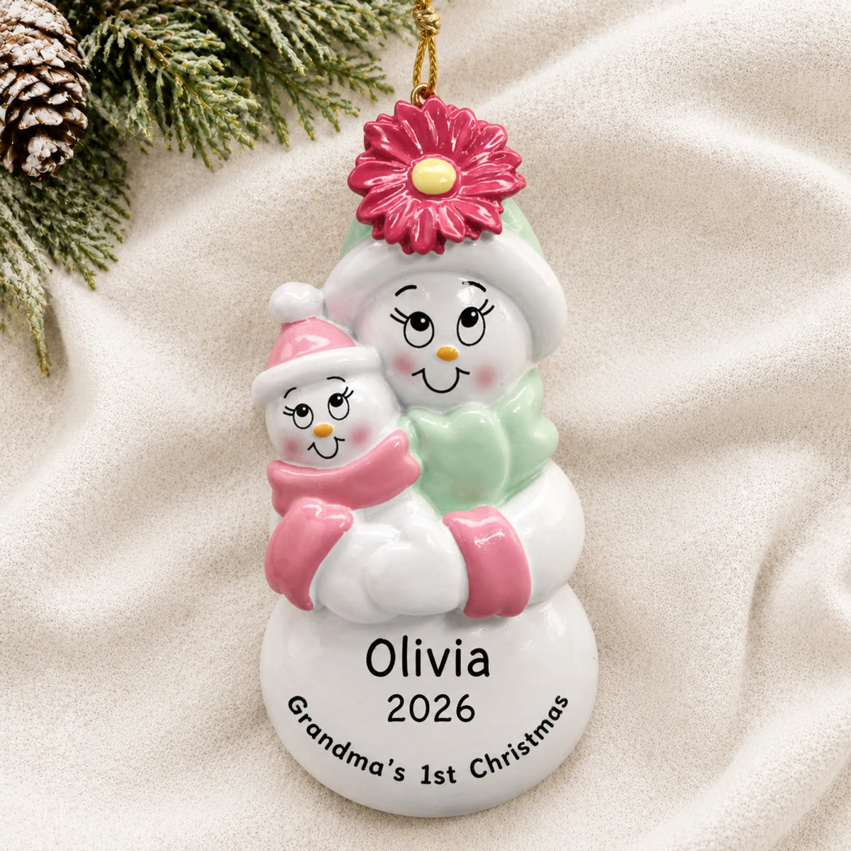 Personalized pink grandma's 1st christmas ornament laid on a soft white knit blanket