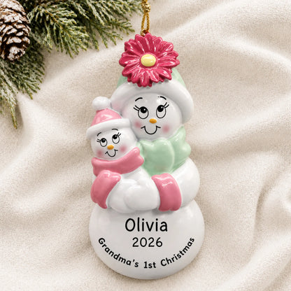 Personalized pink grandma's 1st christmas ornament laid on a soft white knit blanket