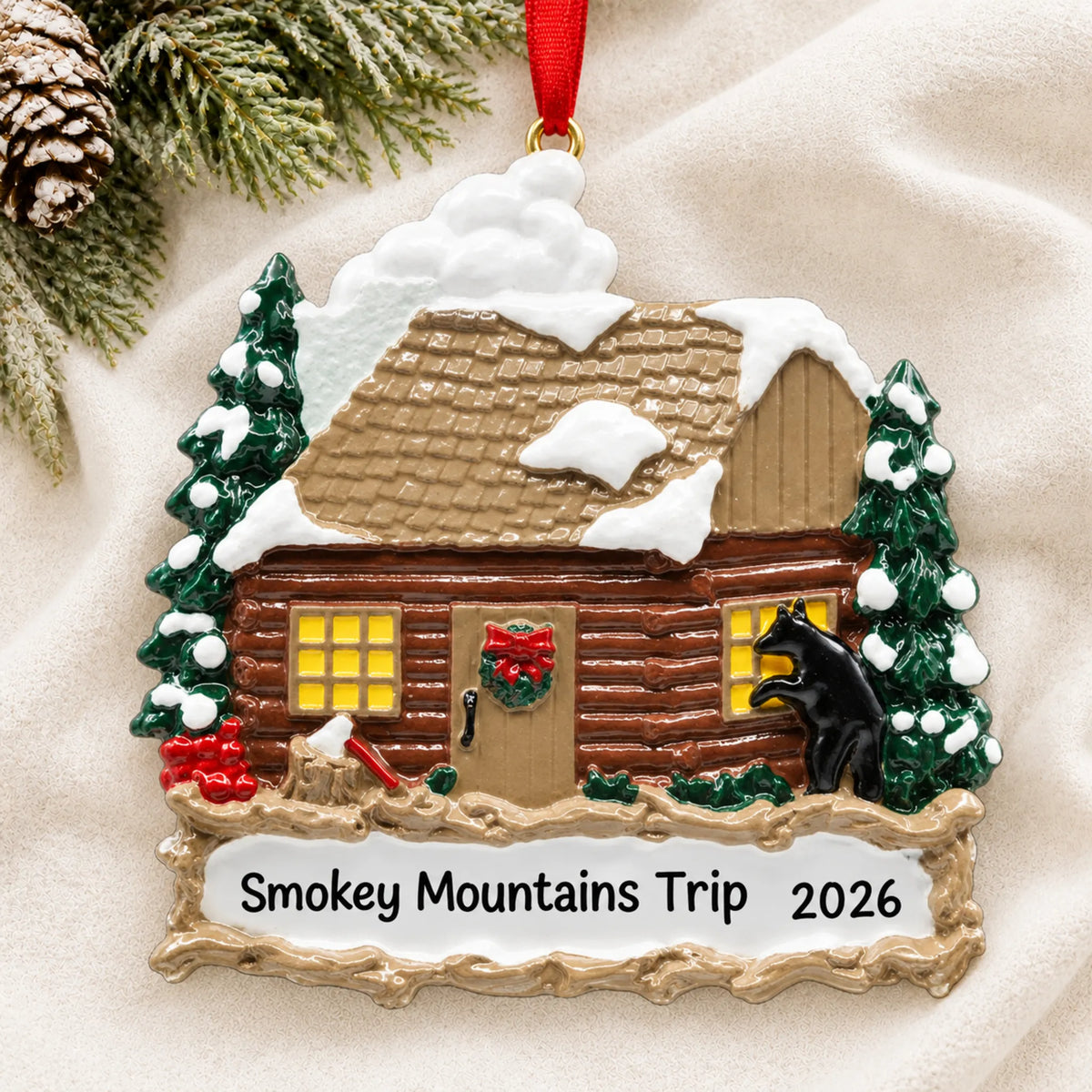 Personalized log cabin with banner christmas ornament laid on a soft white knit blanket