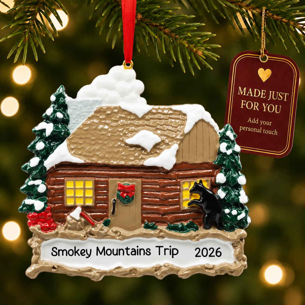 Log cabin with banner christmas ornament hanging on a lit Christmas tree with a Made Just For You gift tag