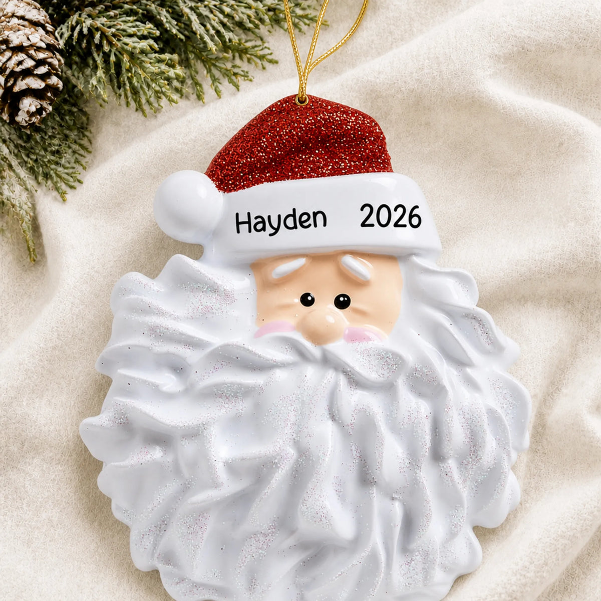 Personalized Santa Glitter Beard christmas ornament laid on a soft white knit blanket