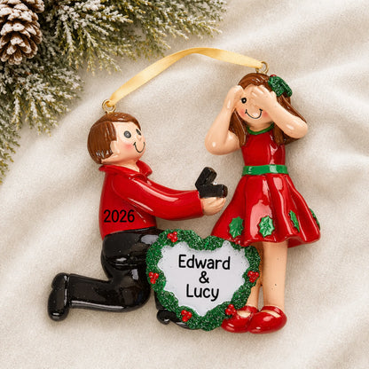 Personalized Proposing Couple christmas ornament laid on a soft white knit blanket