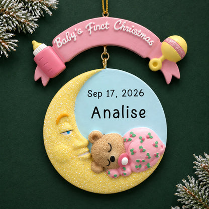 Personalized pink baby's 1st christmas moon ornament on a dark green pine background