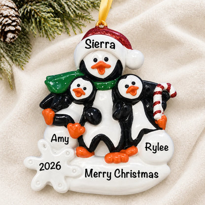 Personalized single parent penguin with 2 kids christmas ornament laid on a soft white knit blanket