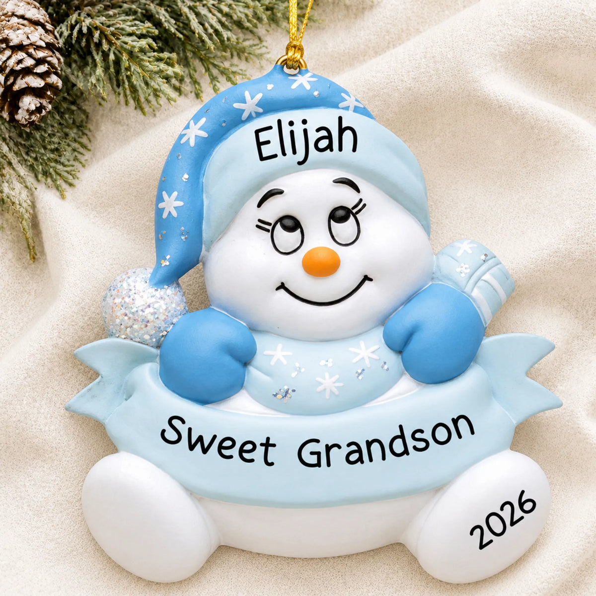 Personalized grandson snowman christmas ornament laid on a soft white knit blanket