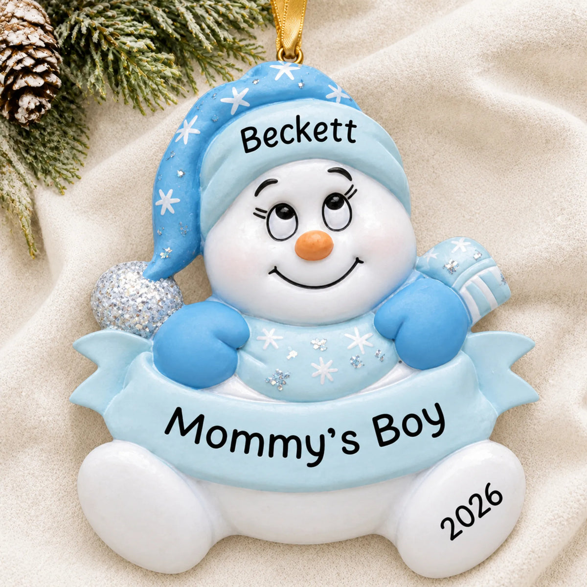 Personalized mommy's boy snowman christmas ornament laid on a soft white knit blanket