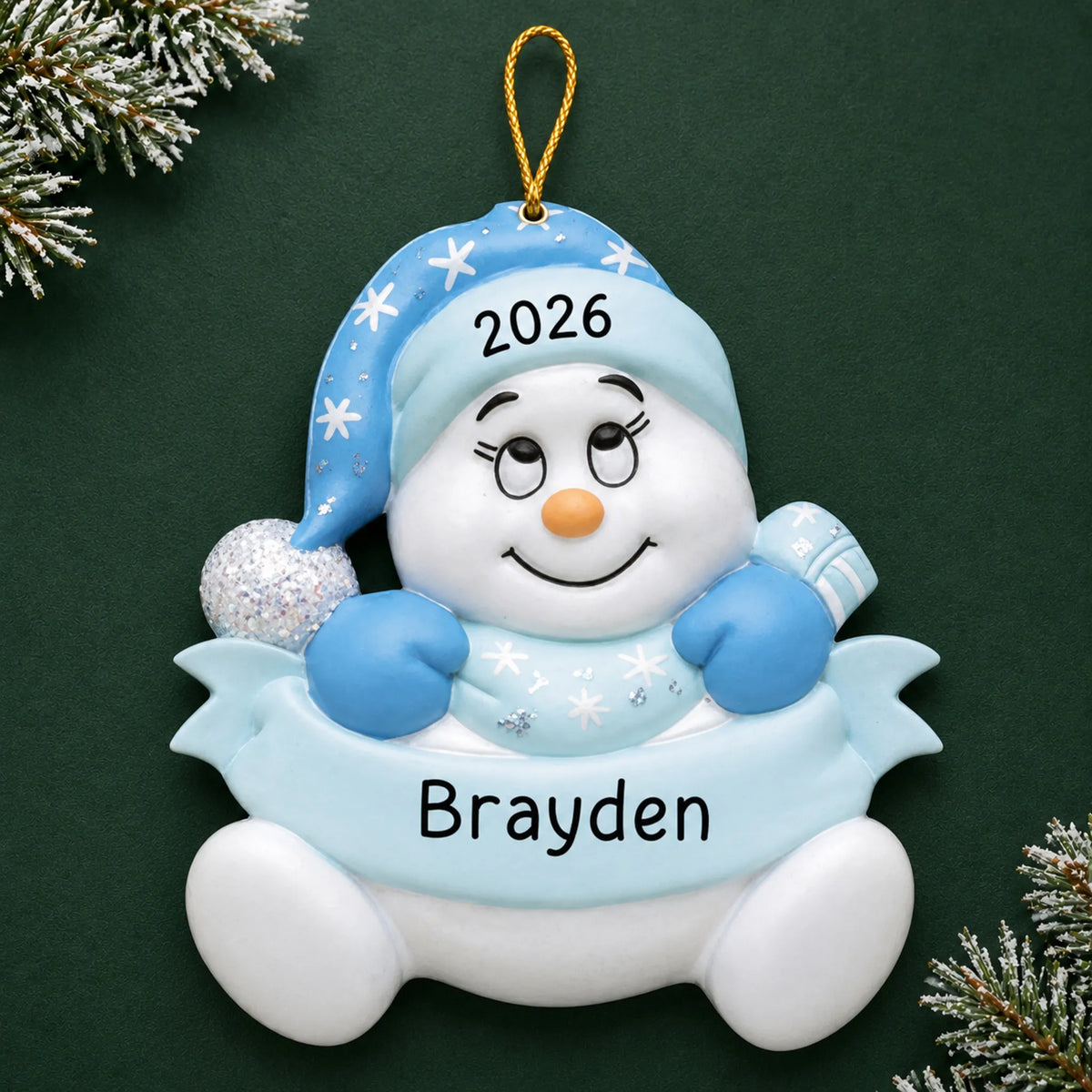 Personalized baby boy blue snowman christmas ornament on a dark green pine background