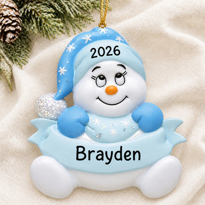 Personalized baby boy blue snowman christmas ornament laid on a soft white knit blanket