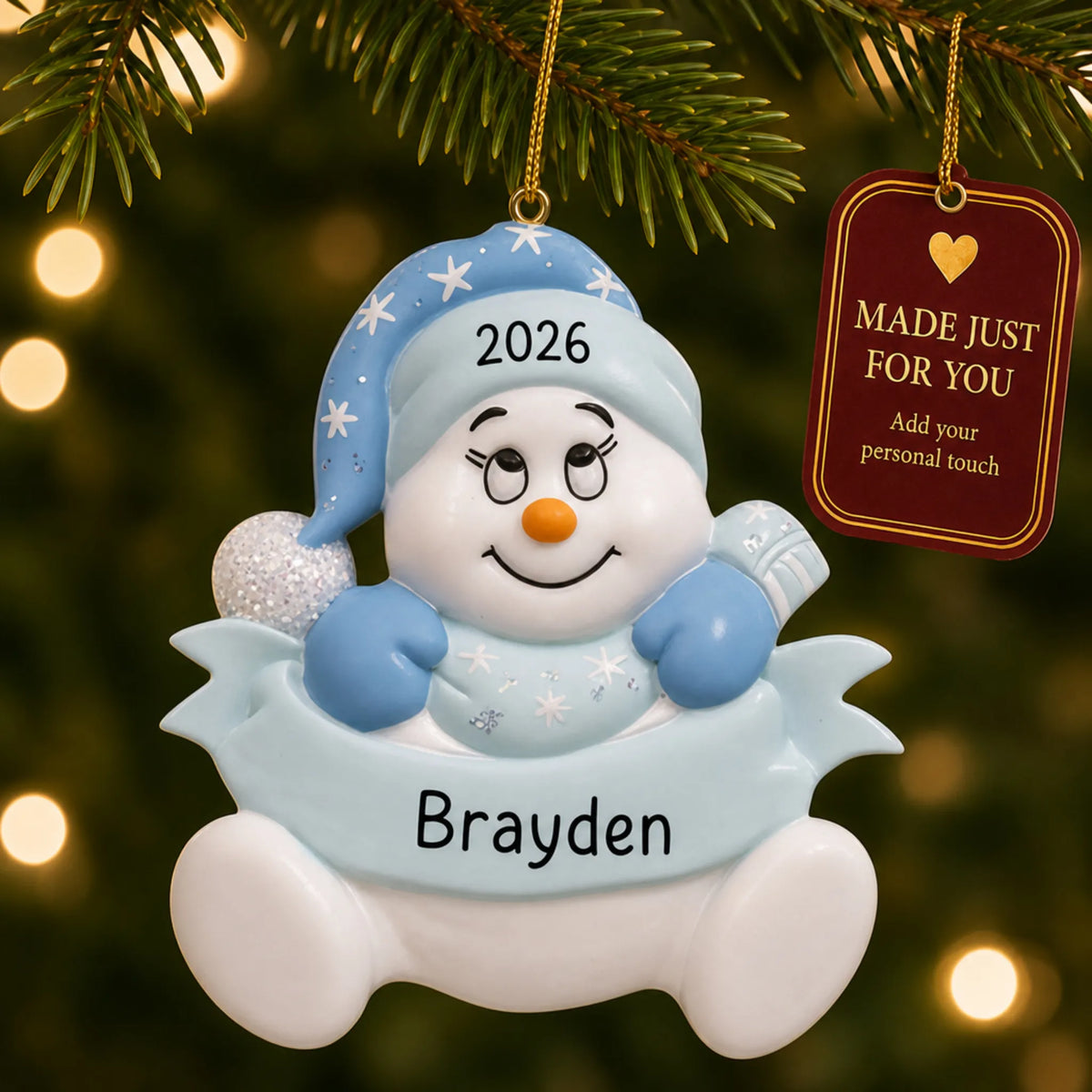Baby boy blue snowman christmas ornament hanging on a lit Christmas tree with a Made Just For You gift tag