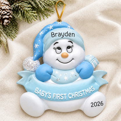 Personalized blue baby's 1st christmas snow baby ornament laid on a soft white knit blanket