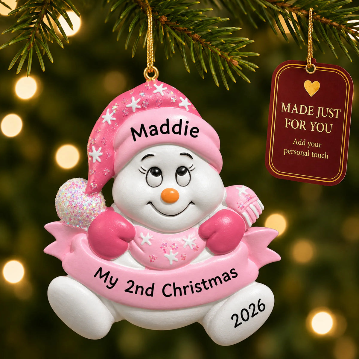 Baby girl 2nd christmas snowman ornament hanging on a lit Christmas tree with a Made Just For You gift tag