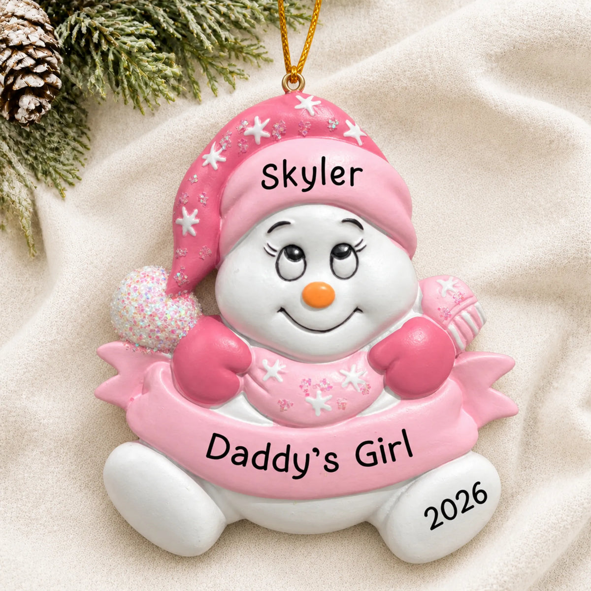 Personalized daddy's girl snowman christmas ornament laid on a soft white knit blanket