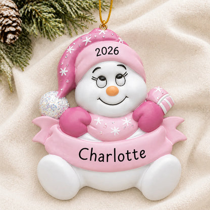 Personalized baby girl pink snowbaby christmas ornament laid on a soft white knit blanket
