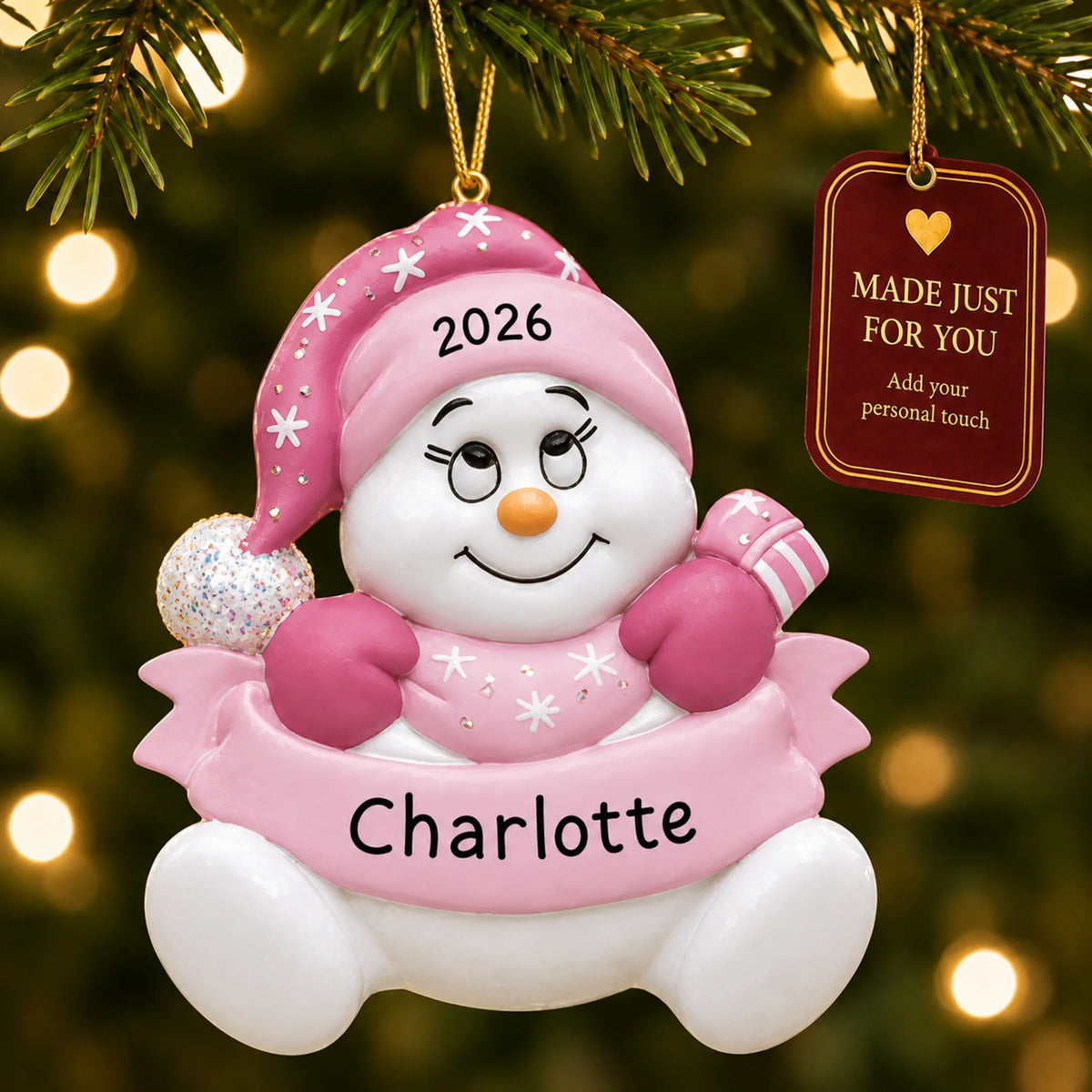 Baby girl pink snowbaby christmas ornament hanging on a lit Christmas tree with a Made Just For You gift tag