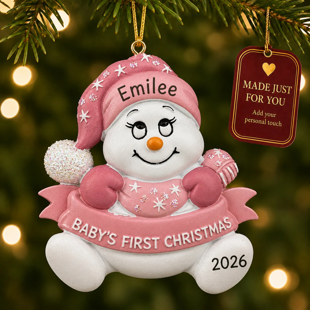 Pink baby's 1st christmas snow baby ornament hanging on a lit Christmas tree with a Made Just For You gift tag