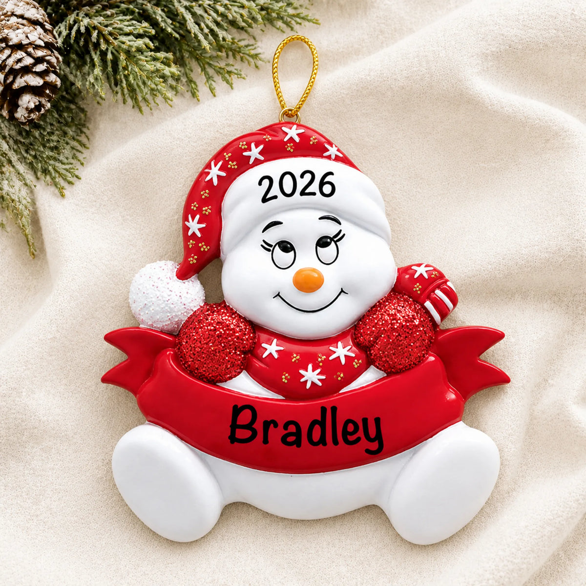 Personalized red snowbaby christmas ornament laid on a soft white knit blanket