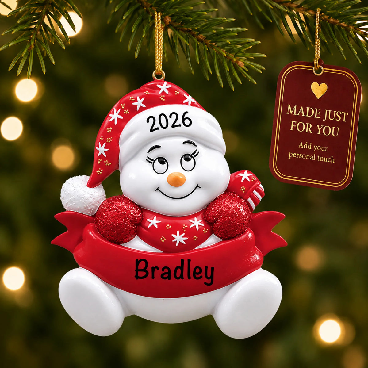 Red snowbaby christmas ornament hanging on a lit Christmas tree with a Made Just For You gift tag