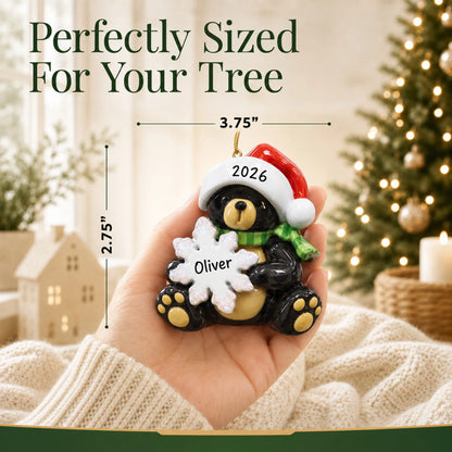 Size guide: the personalized sitting black bear christmas ornament is 3.75 in wide by 2.75 in tall, shown in hand