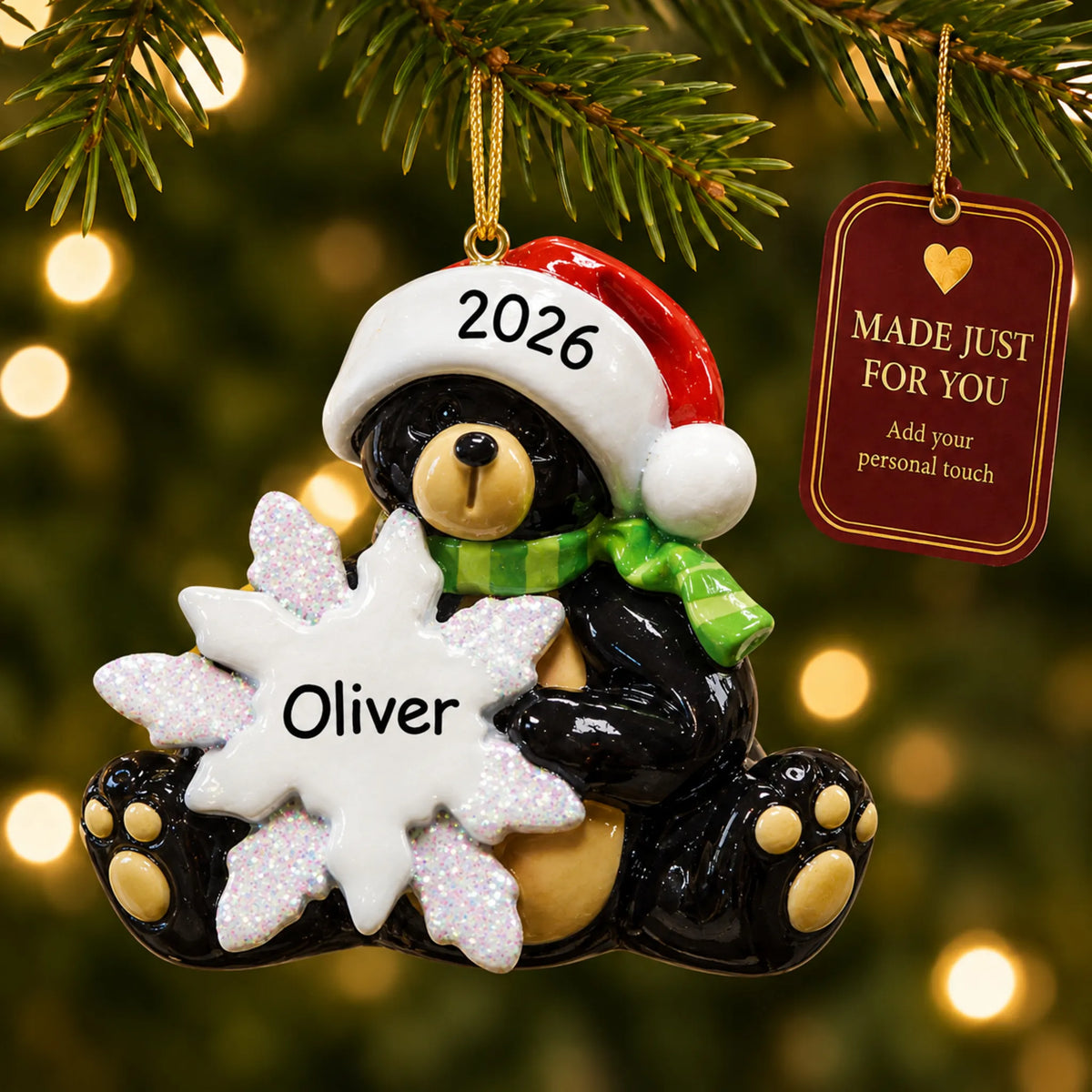 Sitting black bear christmas ornament hanging on a lit Christmas tree with a Made Just For You gift tag