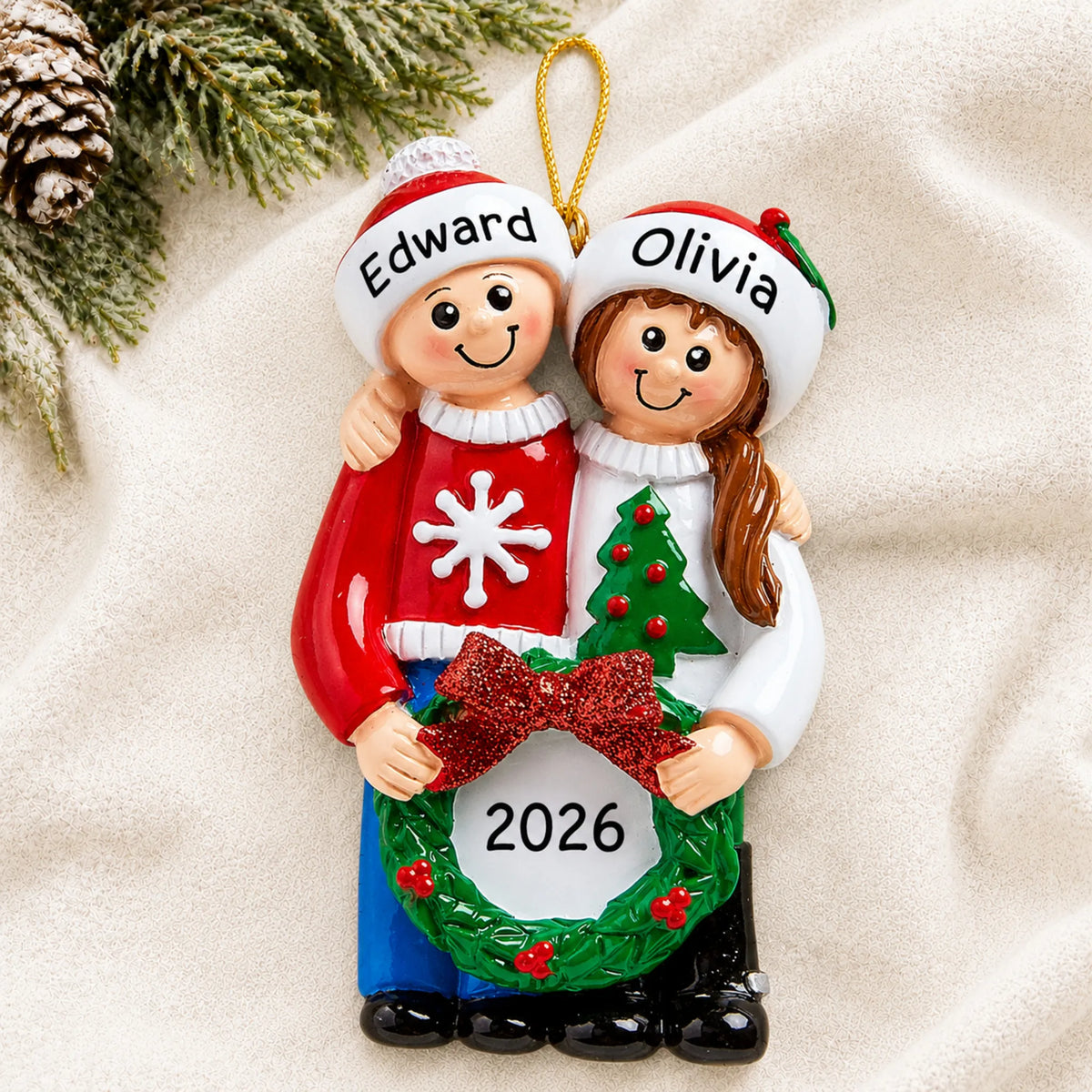 Personalized ugly sweater couple christmas ornament laid on a soft white knit blanket