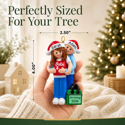 Personalized expecting couple Christmas ornament held in hand to show size, about 2.5 inches wide by 4 inches tall