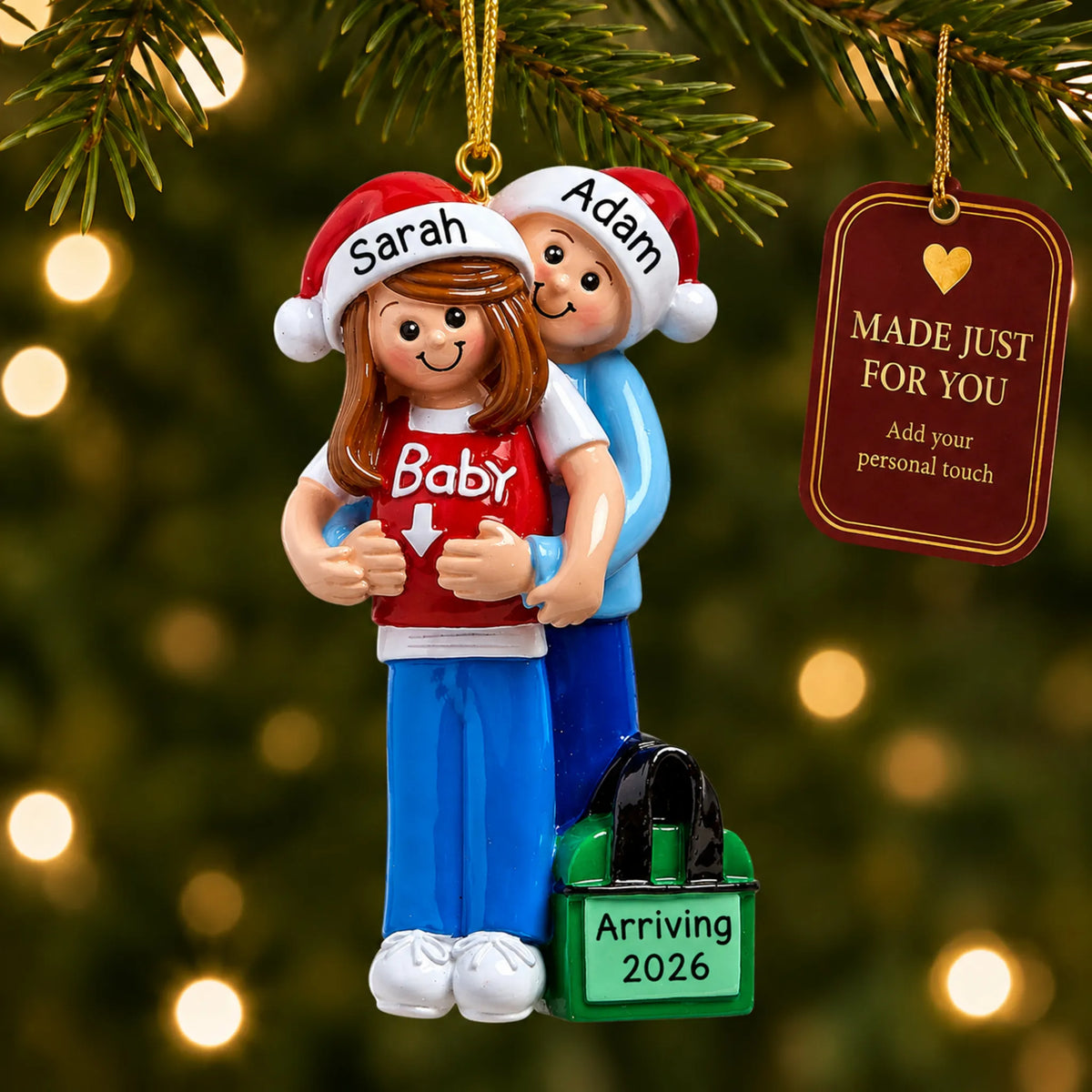 Personalized expecting couple Christmas ornament hanging on a lit Christmas tree beside a Made Just For You gift tag
