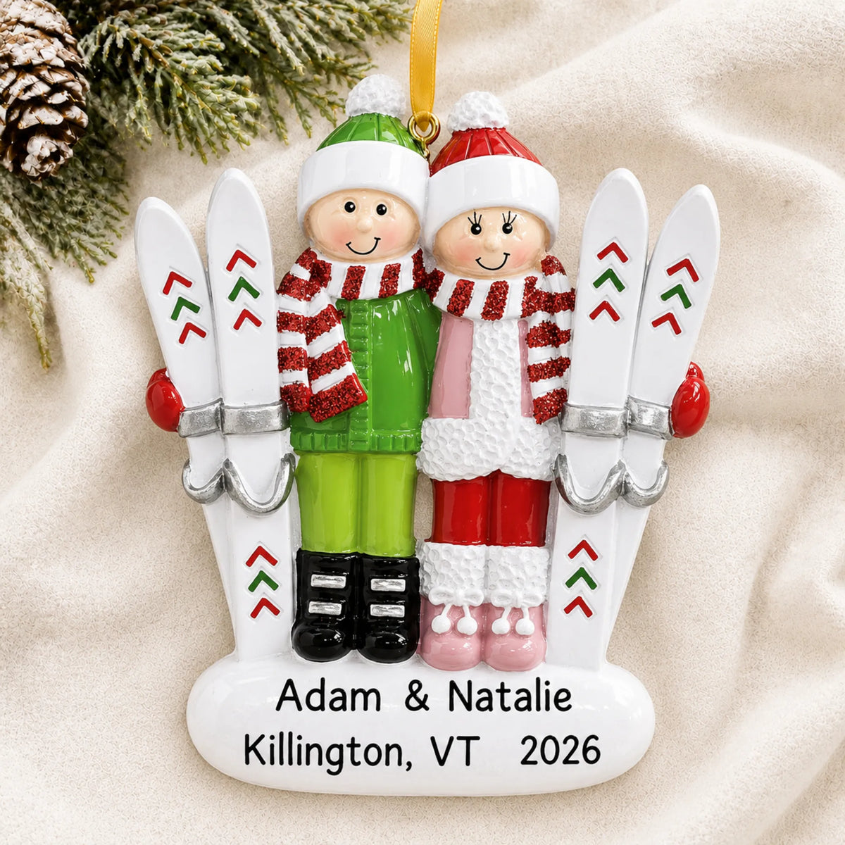 Personalized ski couple christmas ornament laid on a soft white knit blanket