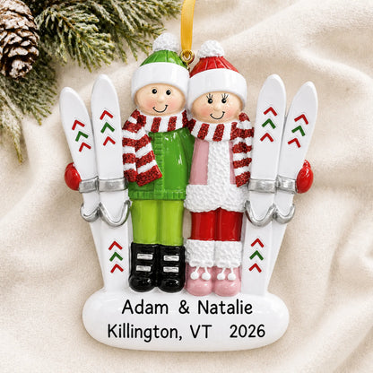 Personalized ski couple christmas ornament laid on a soft white knit blanket