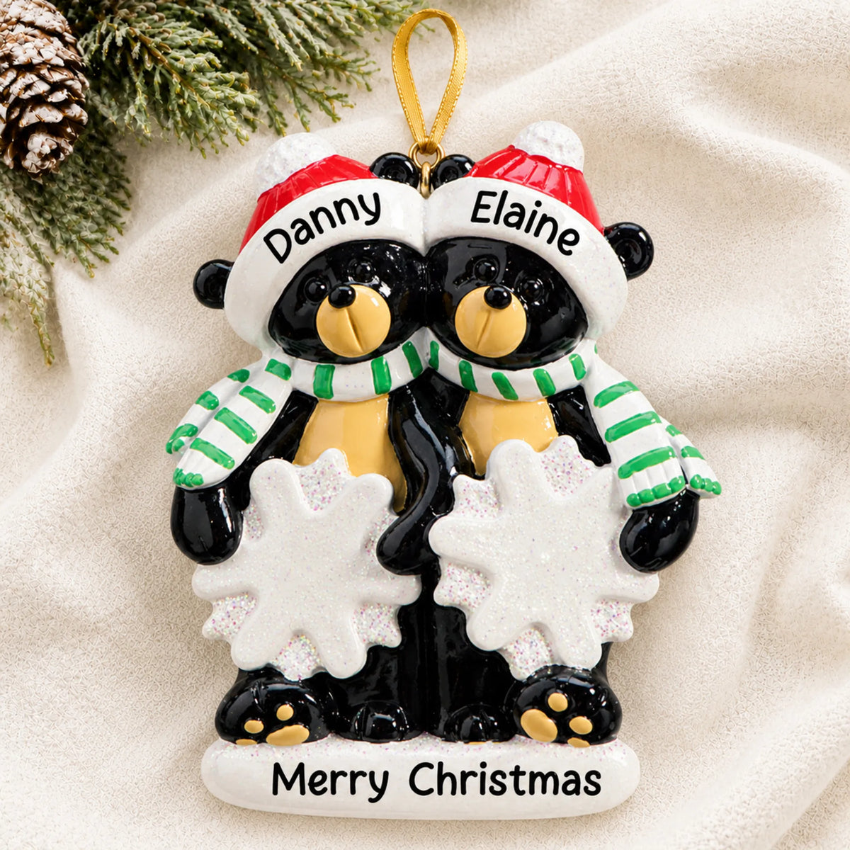Personalized black bear couple christmas ornament laid on a soft white knit blanket