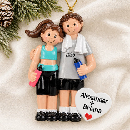 Personalized workout couple christmas ornament laid on a soft white knit blanket