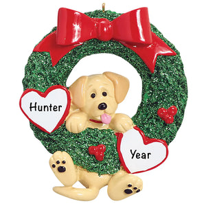 Personalized Yellow Lab Christmas ornament, a Yellow Lab puppy climbing through a green glitter wreath with a red bow, the pet name engraved on one white heart and the year on the other