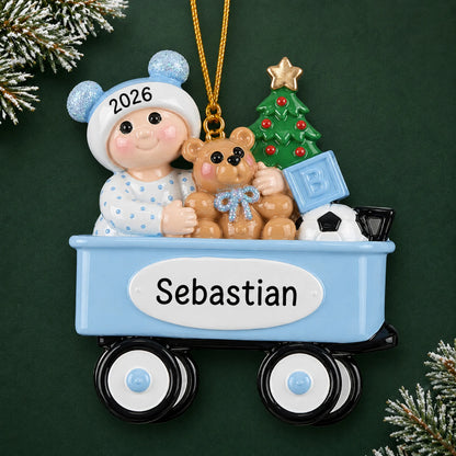Personalized blue wagon baby boy christmas ornament on a dark green pine background