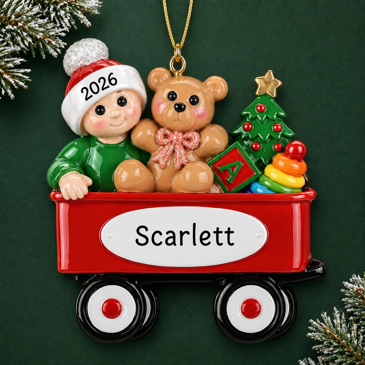 Personalized red wagon baby christmas ornament on a dark green pine background