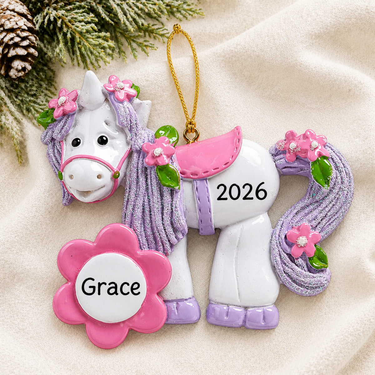 Personalized unicorn flower bloom christmas ornament laid on a soft white knit blanket