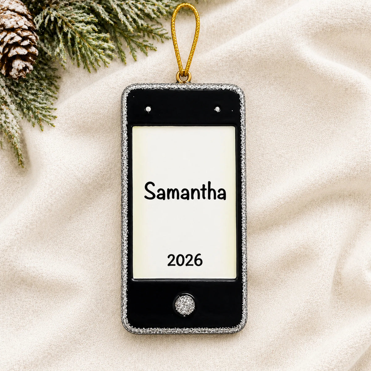 Personalized cell phone christmas ornament laid on a soft white knit blanket