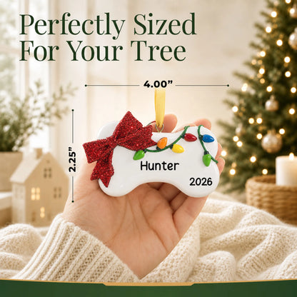 Size guide: the personalized Holiday Lights Dog Bone christmas ornament is 4.00 in wide by 2.25 in tall, shown in hand