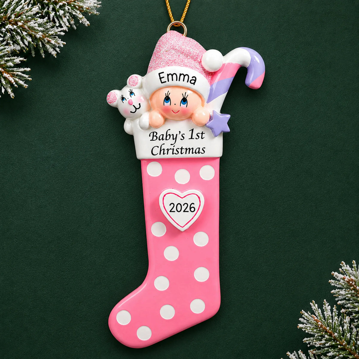 Personalized pink baby's 1st christmas stocking ornament on a dark green pine background