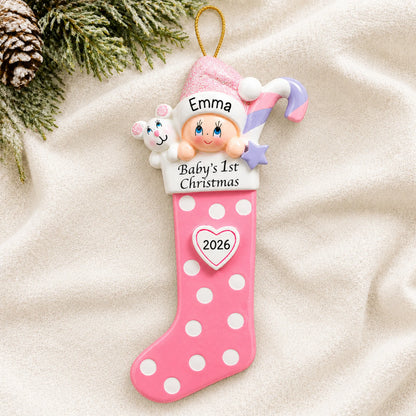 Personalized pink baby's 1st christmas stocking ornament laid on a soft white knit blanket