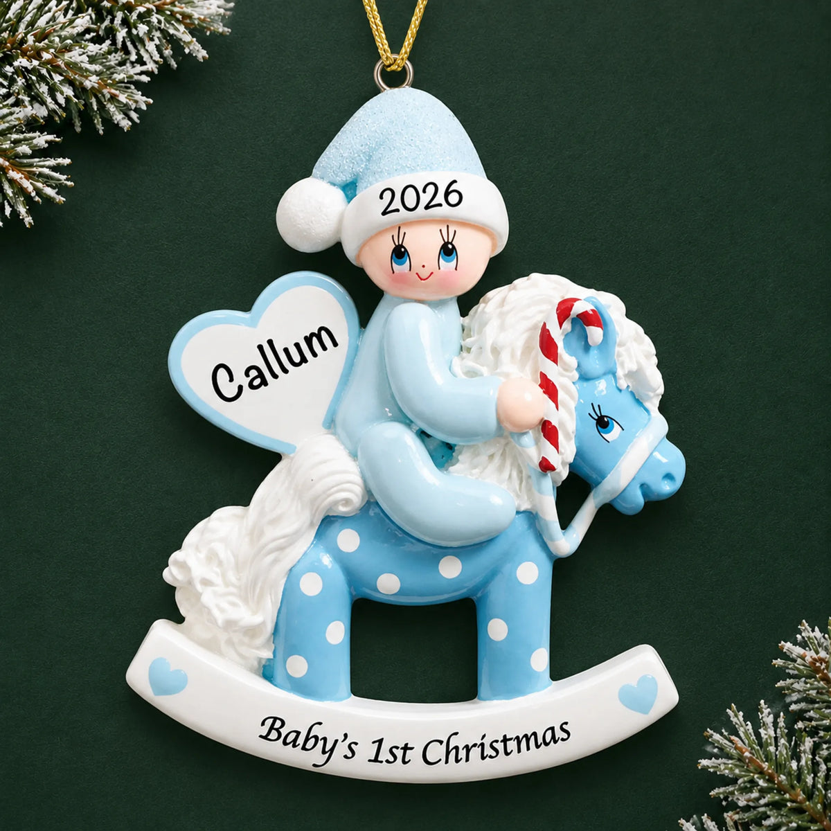 Personalized blue baby's 1st christmas rocking horse ornament on a dark green pine background