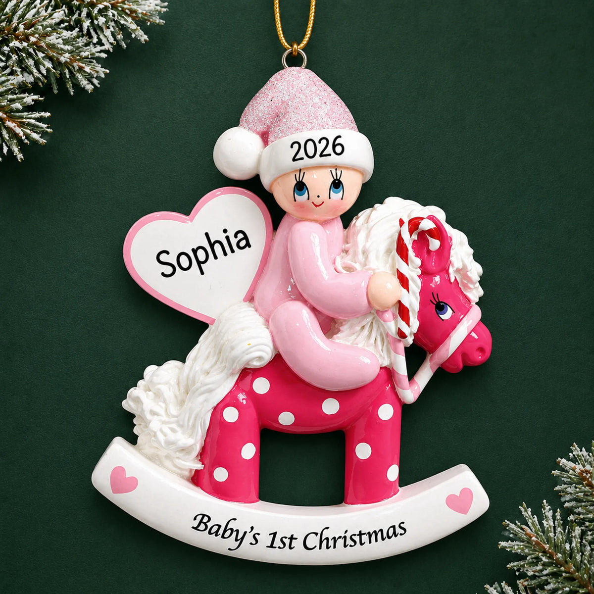 Personalized pink baby's 1st christmas rocking horse ornament on a dark green pine background