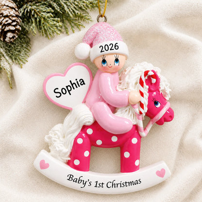 Personalized pink baby's 1st christmas rocking horse ornament laid on a soft white knit blanket