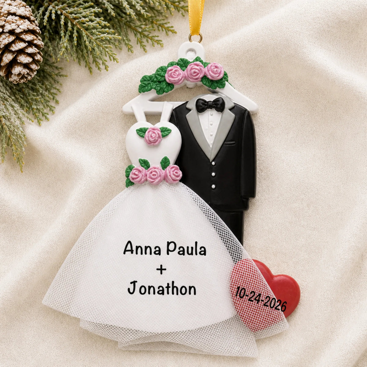 Personalized bride and groom attire Christmas ornament on a cream knit blanket beside pine and pinecones