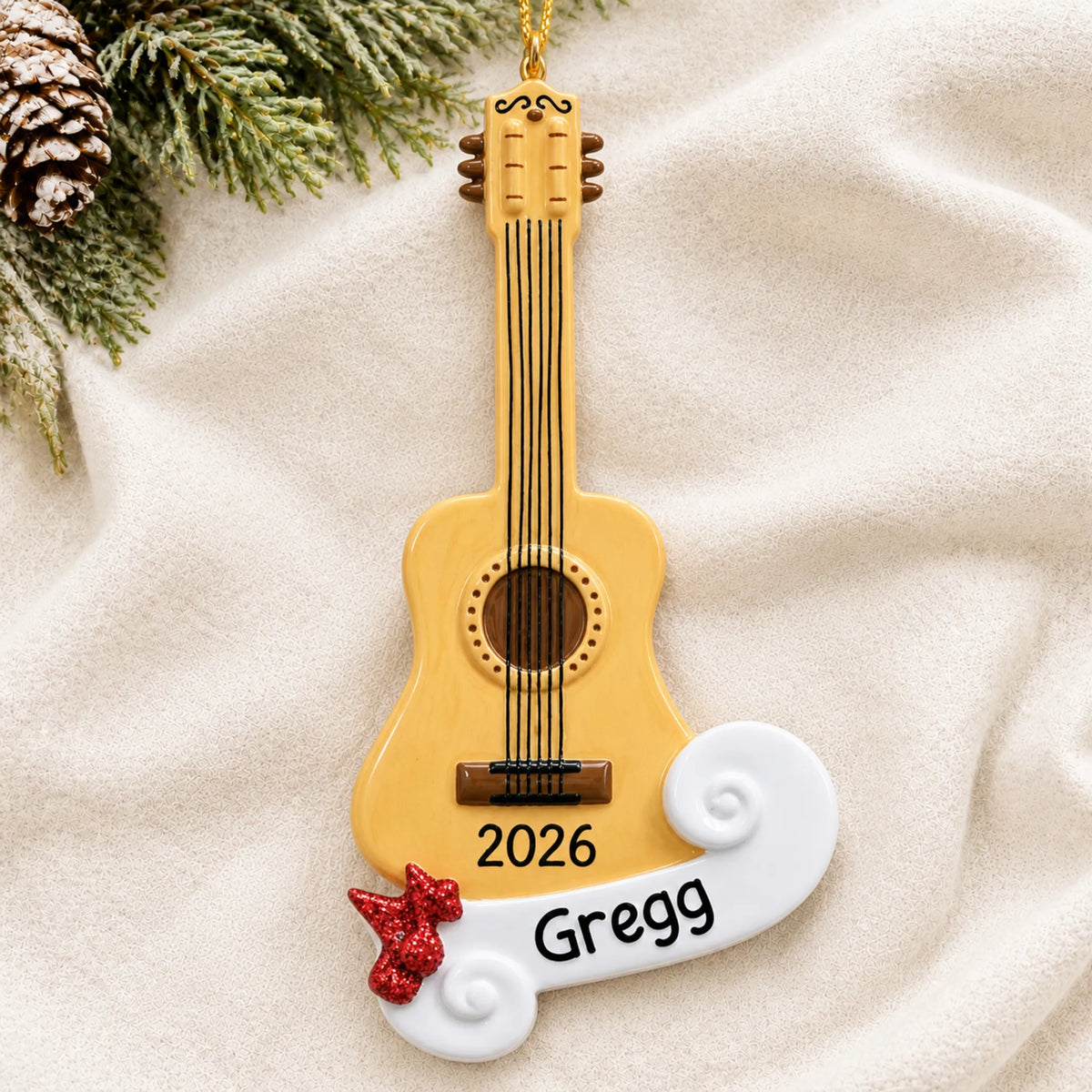 Personalized acoustic guitar christmas ornament laid on a soft white knit blanket