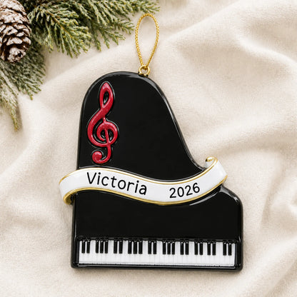 Personalized grand piano christmas ornament laid on a soft white knit blanket