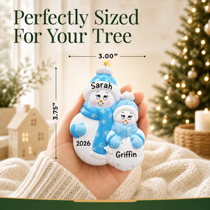 Size guide: the personalized single parent snowman with 1 child christmas ornament shown in hand next to a Christmas tree