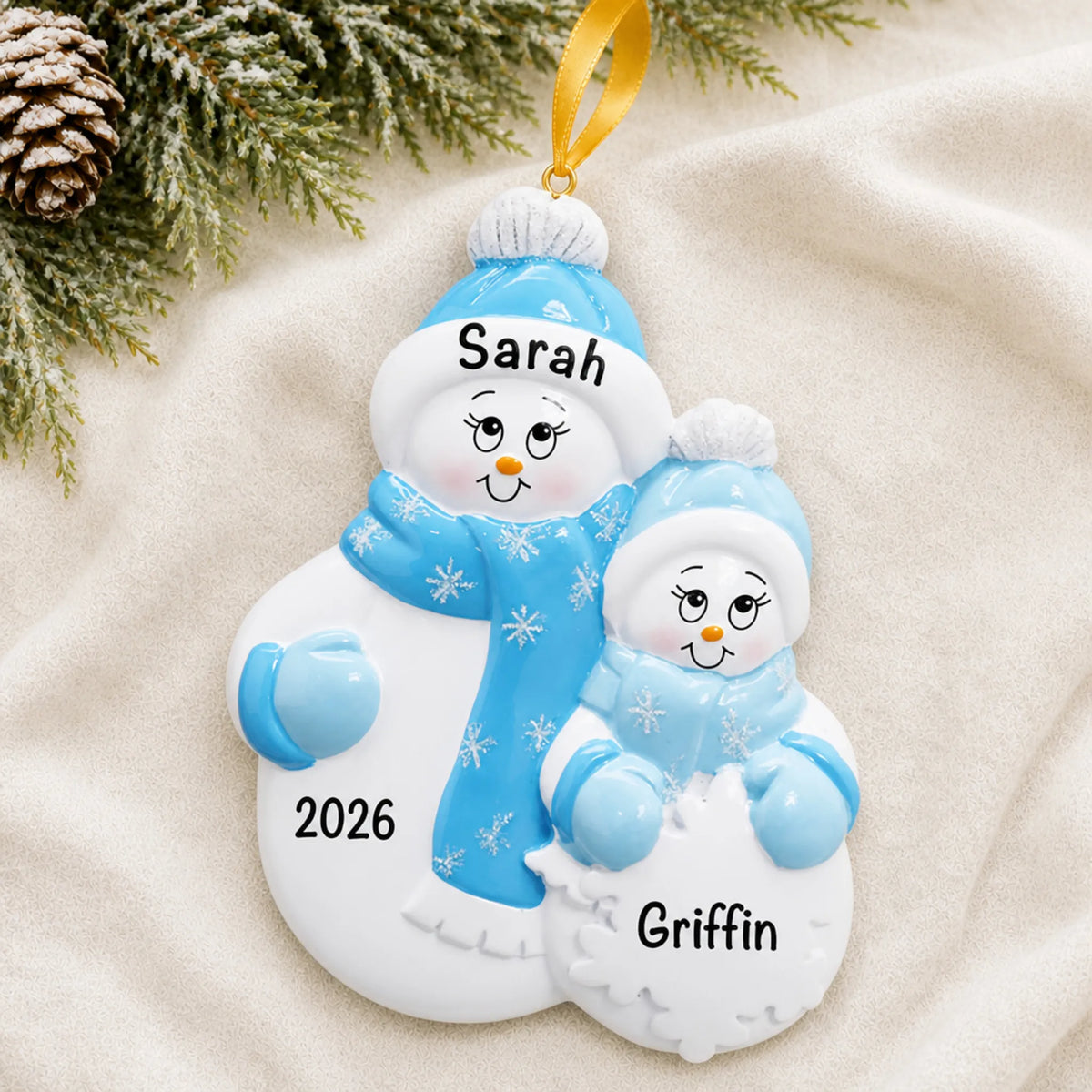 Personalized single parent snowman with 1 child christmas ornament laid on a soft white knit blanket