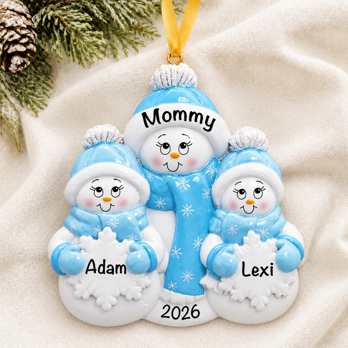 Personalized single parent snowman with 2 children christmas ornament laid on a soft white knit blanket